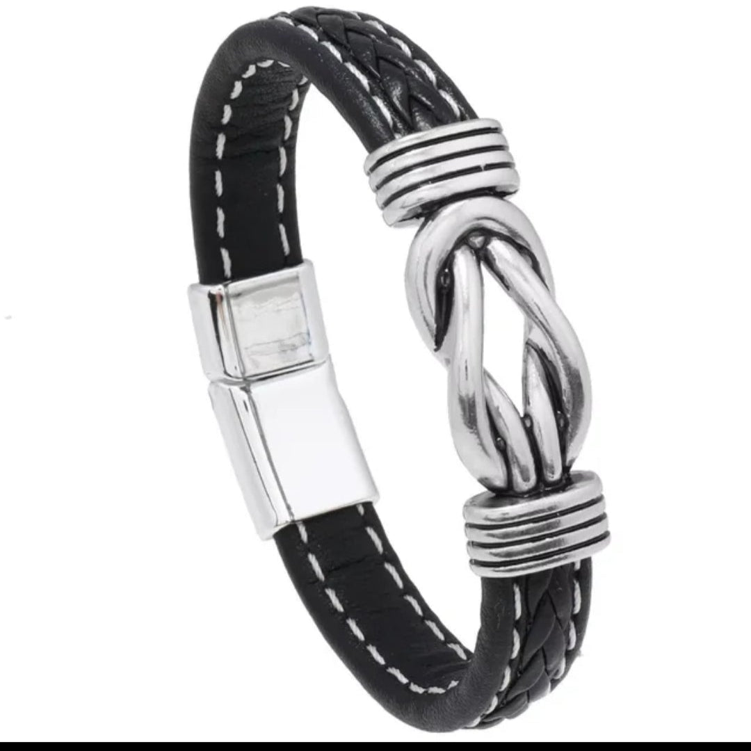Black and white braided bracelet with a silver clasp on a black background