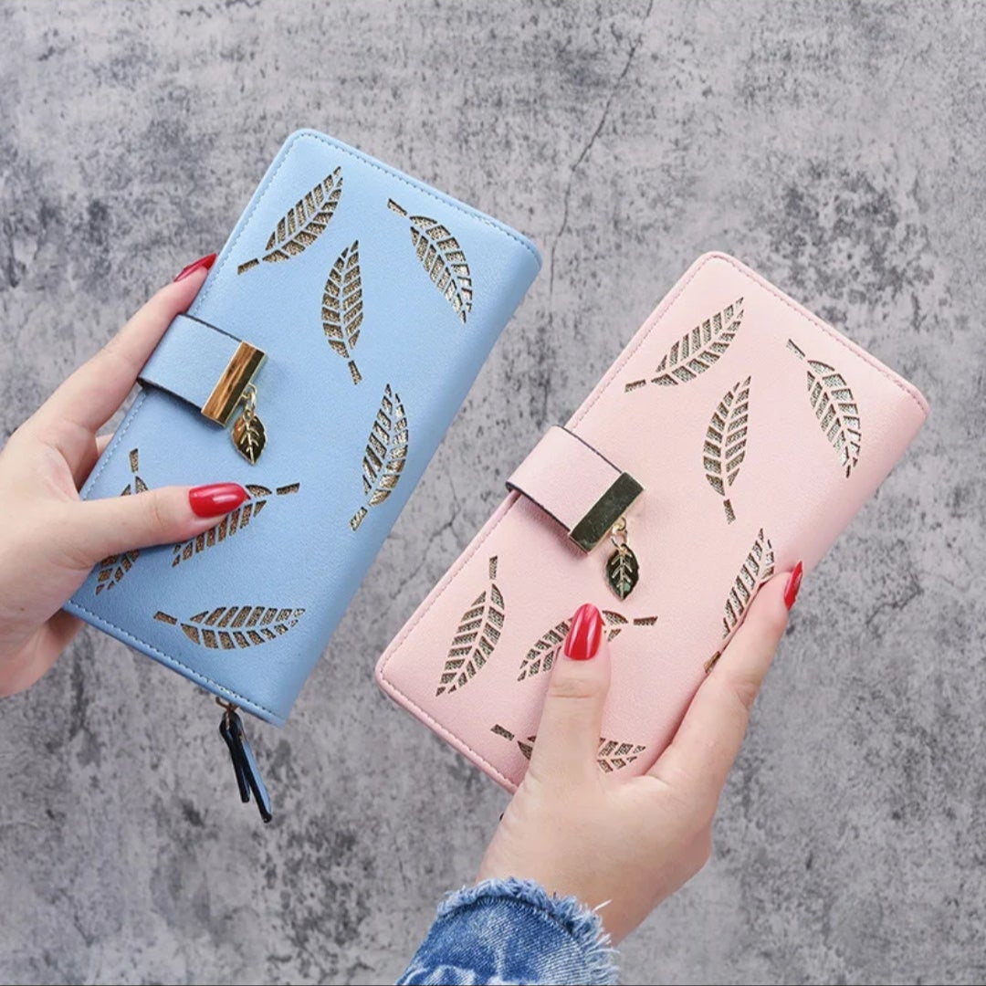 Two hands holding a blue and a pink wallet with leaf designs on a gray background.